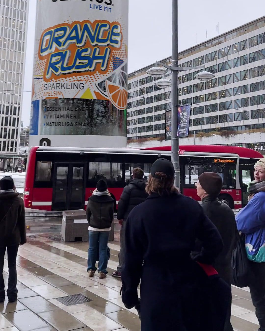 A red bus drives past in front of the 20 metre Orange Rush can at Sergels torg